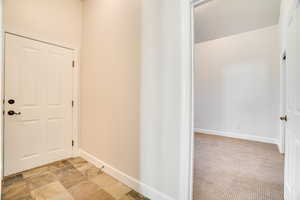 Hallway featuring light stone finish floors and light colored carpet