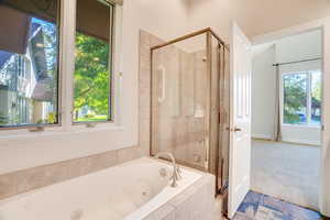 Bathroom featuring a stall shower, a whirlpool tub, and carpet flooring