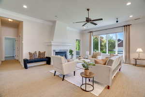 Living area featuring light carpet, crown molding, a tiled fireplace, recessed lighting, and a ceiling fan