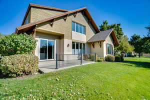 Back of property with a yard, stucco siding, and roof with shingles