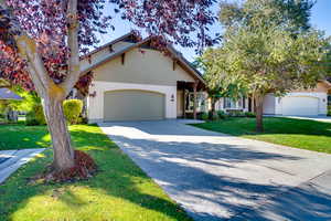 View of front of home with a front yard, concrete driveway, and a garage