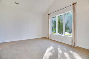 Empty room with light colored carpet and vaulted ceiling