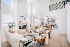 Living room featuring a high ceiling, light wood-style floors, and a tile fireplace