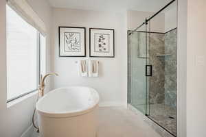Full bathroom featuring a freestanding tub, a shower stall, and tile patterned flooring