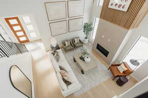 Living area featuring wood finished floors, a towering ceiling, and a tile fireplace