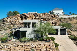 Modern home featuring stucco siding, a balcony, driveway, and an attached garage