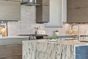 Kitchen with modern cabinets, light stone counters, tasteful backsplash, and stainless steel range with gas stovetop