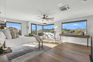Bedroom featuring cooling unit, multiple windows, wood-type flooring, and a ceiling fan