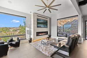 Living area featuring a tile fireplace, vaulted ceiling, and a ceiling fan