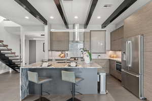 Kitchen featuring modern cabinets, light stone countertops, stainless steel appliances, a kitchen bar, and tasteful backsplash