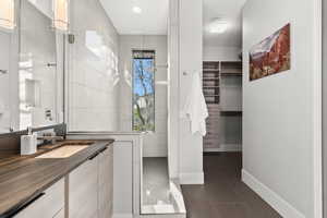 Full bath featuring a spacious closet, vanity, dark tile patterned floors, and recessed lighting