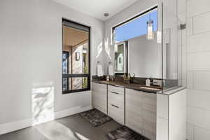 Full bath with double vanity and dark tile patterned flooring