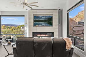 Living area featuring a tiled fireplace and a ceiling fan
