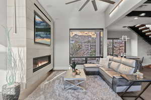 Living area featuring a fireplace, a ceiling fan, and lofted ceiling