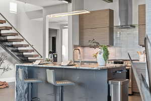 Kitchen with stainless steel range oven, a kitchen bar, decorative backsplash, light stone countertops, and two tone color scheme