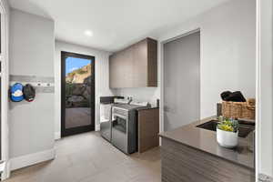 Kitchen with modern cabinets, light tile patterned floors, washer and dryer, dark countertops, and recessed lighting