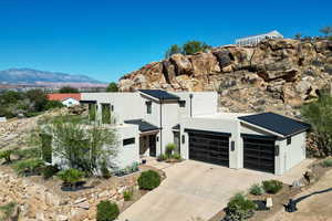 Contemporary house with a standing seam roof, a metal roof, stucco siding, and concrete driveway