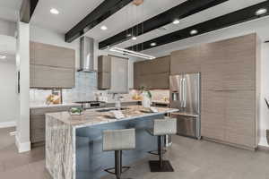 Kitchen with light stone countertops, tasteful backsplash, appliances with stainless steel finishes, a breakfast bar, and beam ceiling