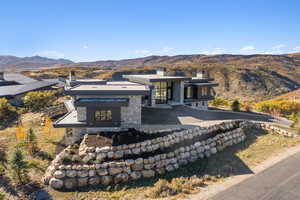 Rear view of house with a chimney, a mountain view, and stone siding