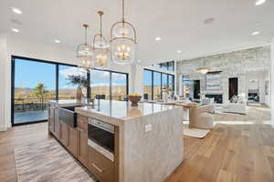 Kitchen with light stone counters, recessed lighting, a large fireplace, decorative light fixtures, and light wood-type flooring