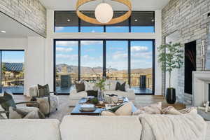 Living room featuring a mountain view, a large fireplace, wood finished floors, a towering ceiling, and brick wall