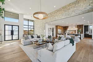 Living area with a towering ceiling, recessed lighting, light wood-style floors, expansive windows, and french doors