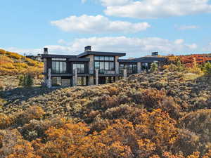 Back of house featuring a balcony and stone siding