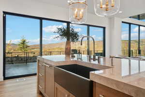 Kitchen with a mountain view, light stone counters, hanging light fixtures, light wood-style floors, and light brown cabinets