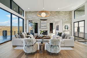 Living area featuring hardwood / wood-style flooring, a fireplace, a high ceiling, recessed lighting, and french doors