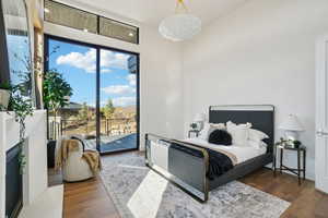 Bedroom with dark wood-style flooring, access to exterior, and a fireplace with raised hearth