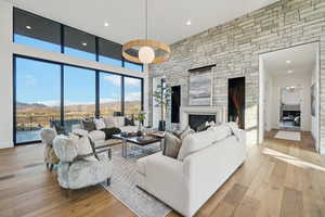 Living area with a fireplace, a mountain view, recessed lighting, light wood-type flooring, and a high ceiling