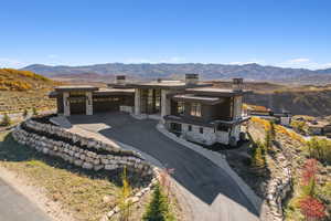 Contemporary home with stone siding, a mountain view, and driveway