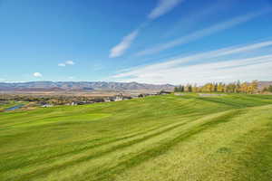 View of home's community featuring view of golf course, a mountain view, and a lawn