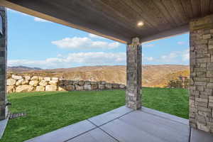 View of green lawn with a patio area and a mountain view