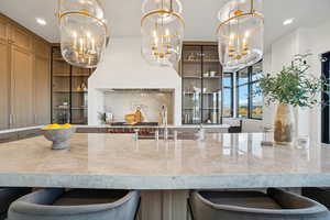 Kitchen featuring a kitchen bar, recessed lighting, light stone counters, pendant lighting, and tasteful backsplash