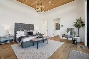 Bedroom featuring wood ceiling, wood finished floors, a towering ceiling, and a chandelier