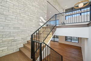 Stairway with wood finished floors, a high ceiling, and recessed lighting