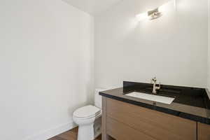 Half bathroom with vanity and dark wood-style flooring
