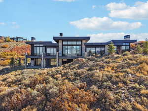Rear view of house featuring a patio area, stone siding, and a balcony