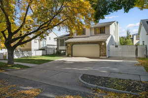 View of front of home featuring a gate, brick siding, concrete driveway, a garage, and roof with shingles