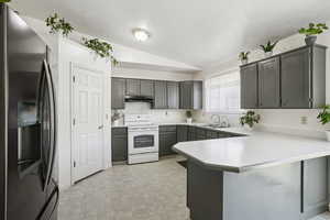 Kitchen with stainless steel refrigerator with ice dispenser, a peninsula, white electric range oven, light countertops, and a textured ceiling
