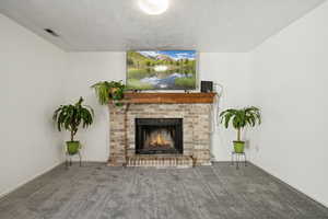 Unfurnished living room featuring carpet floors, a textured ceiling, and a fireplace