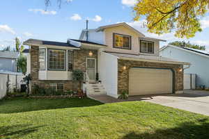 Split level home featuring brick siding, driveway, and an attached garage