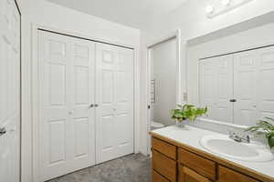 Full bathroom featuring a closet, vanity, dark carpet, and a textured ceiling