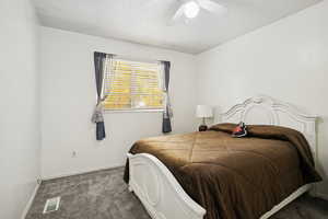 Carpeted bedroom with a ceiling fan and a textured ceiling