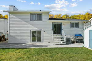 Rear view of property featuring a patio area, a yard, and a chimney