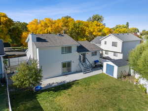 Back of house with a storage shed, a fenced backyard, a patio, and roof with shingles