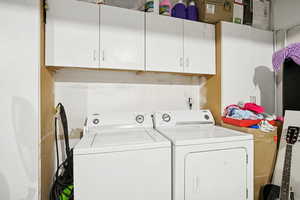 Washroom featuring washing machine and clothes dryer and cabinet space