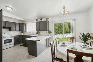 Kitchen featuring white electric range oven, light countertops, a peninsula, healthy amount of natural light, and a textured ceiling