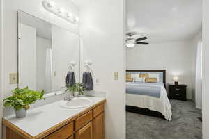Bathroom featuring dark carpet, vanity, a textured ceiling, ensuite bath, and a ceiling fan